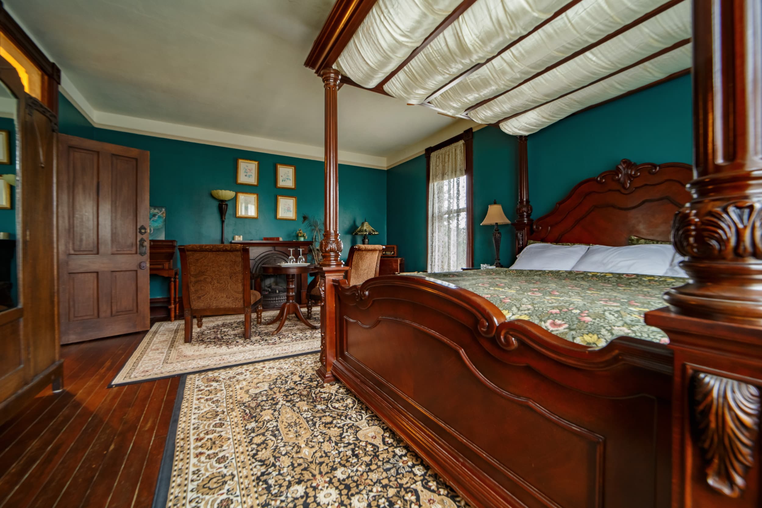 Romantic four-poster king bed with a draped canopy and ornate dark wood frame.
