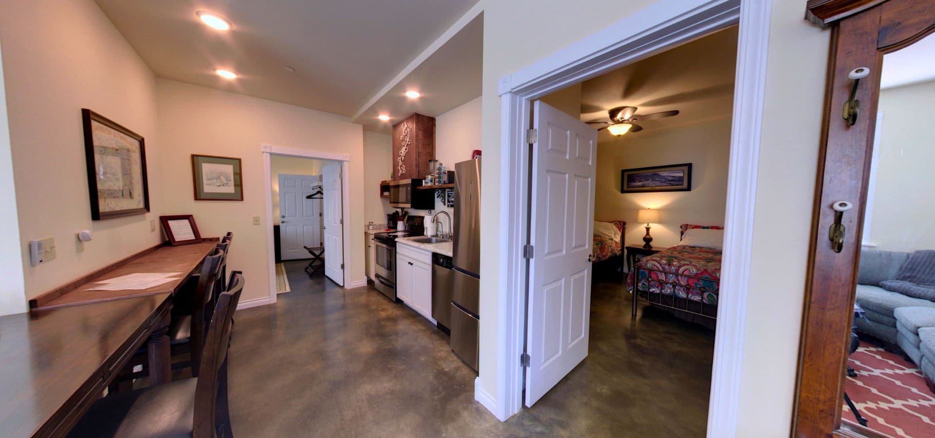 A compact kitchen with modern appliances opens into a cozy bedroom area, showcasing a welcoming interior design.